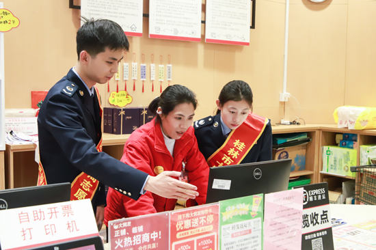 超市工作人员向税务干部介绍扫码开票。桂林市七星区税务局供图