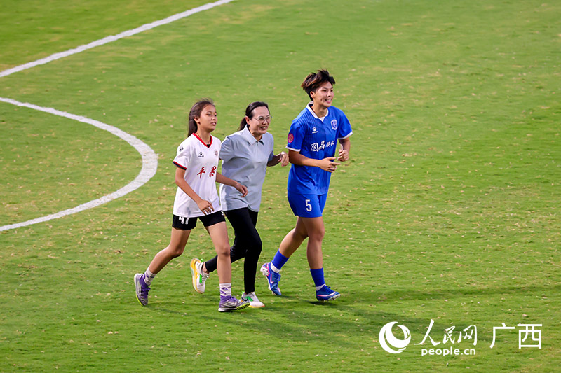 广西籍足球名宿、前女足国脚韦海英登场，与呗侬女足现役球员潘彦宏还有青训小将进行互动。人民网记者 严立政摄