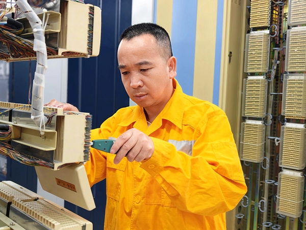 图一 韦列锋在通信机房内完成线缆卡接与调试作业。王万强 摄