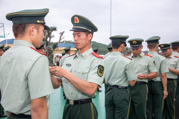 武警官兵为新入团官兵佩戴团徽。