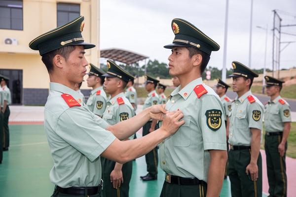武警官兵为新入团官兵佩戴团徽。