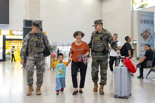 武警官兵协助老人搬运行李。