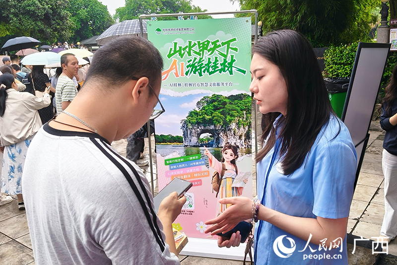 工作人员现场指导游客使用“AI桂林”。人民网 刘璐瑶摄