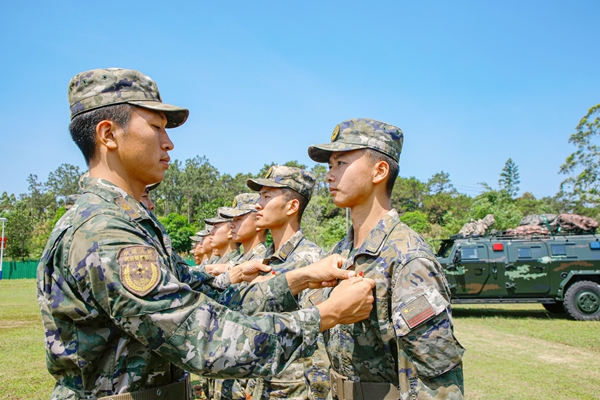 武警官兵代表為新入團青年官兵佩戴團徽 。