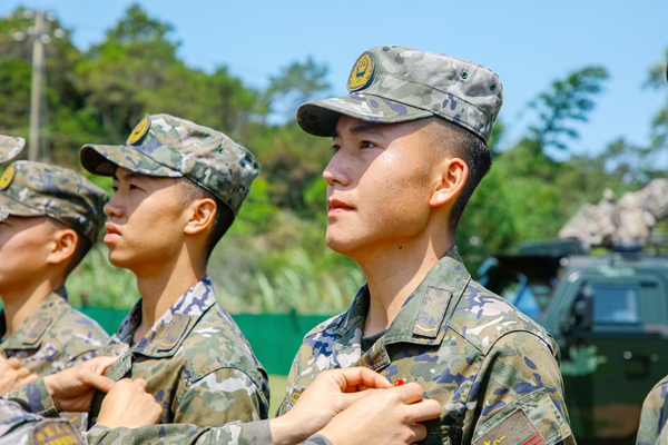 武警官兵代表為新入團青年官兵佩戴團徽。