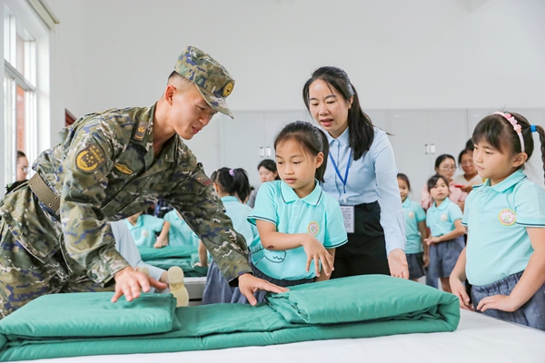 武警官兵為學生演示疊軍被。