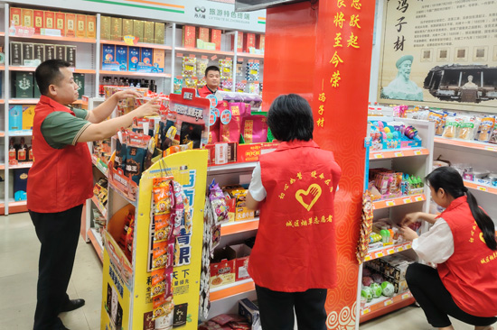 图为城区烟草志愿者在旅游特色终端店内帮助零售户打造整理。吴钦德摄