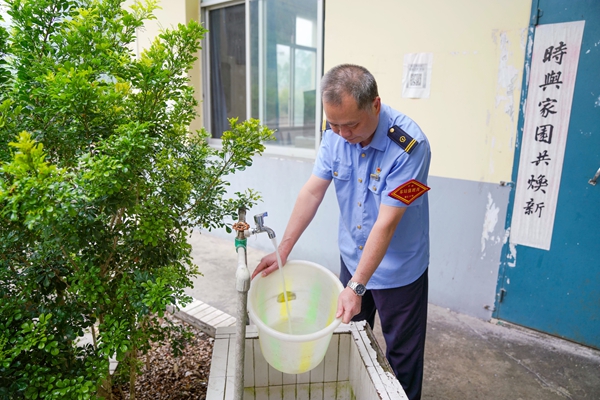 覃獻杰用水桶接新井清澈的水。