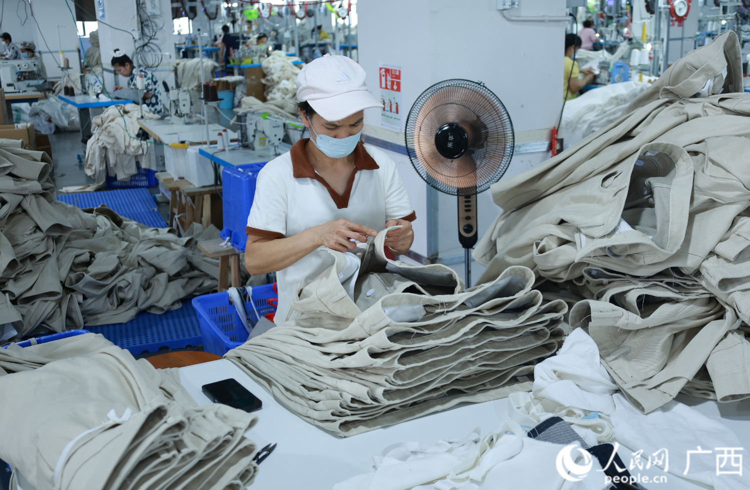 工人在处理腰袢上的线头，完工后便是成品牛仔裤。人民网 韦欢摄