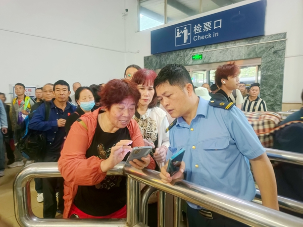 金城江站客运工作人员为旅客解答问讯。覃晓平摄