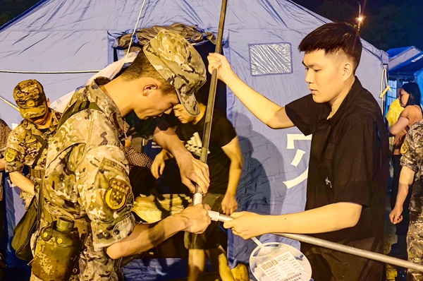 武警官兵与地方群众搭建应急帐篷。赖治华摄