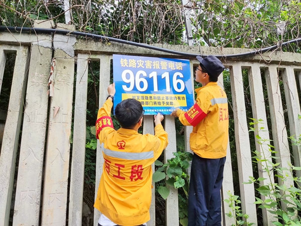 百色工務段作業人員正在田東-田陽區間內粘貼警示電話，引導沿線群眾發現鐵路險情及時電話通報情況。韋森攝.jpg
