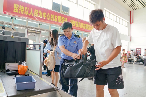全州南站工作人员服务旅客安检进站。卢穗萍摄