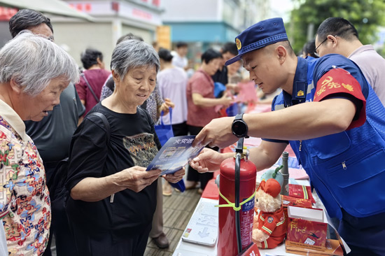 图为消防宣传员为群众科普火灾逃生知识，何小翠摄