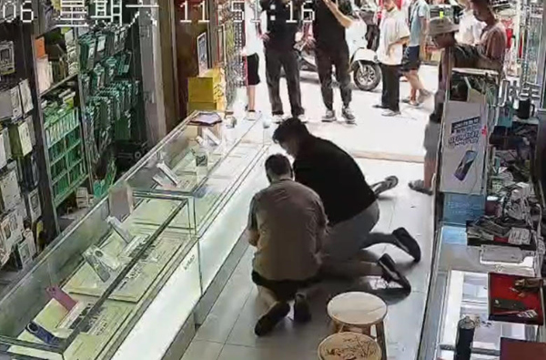中国联通南宁市分公司三塘网格总监韦武庆跪地为患者实施心肺复苏。中国联通广西分公司供图。