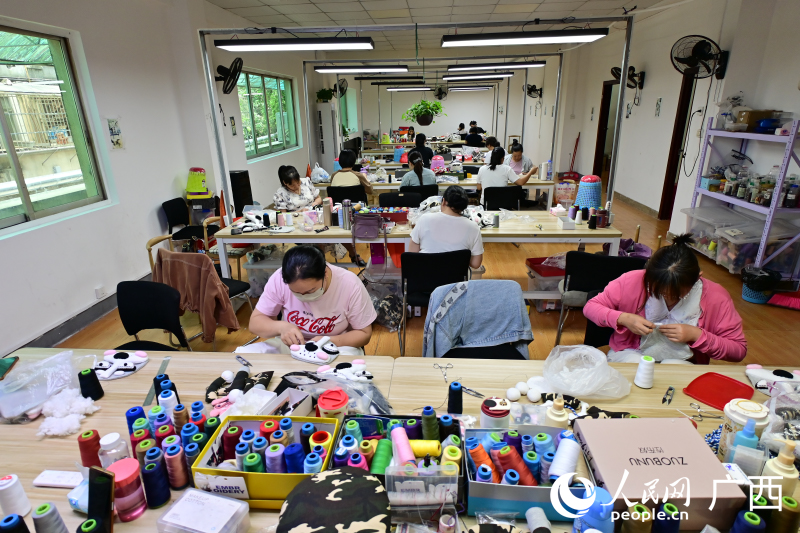 绣娘们正在缝制手工品。人民网记者 雷琦竣摄