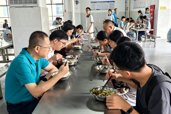 在学校食堂与学生共同进餐。八步区教育局供图