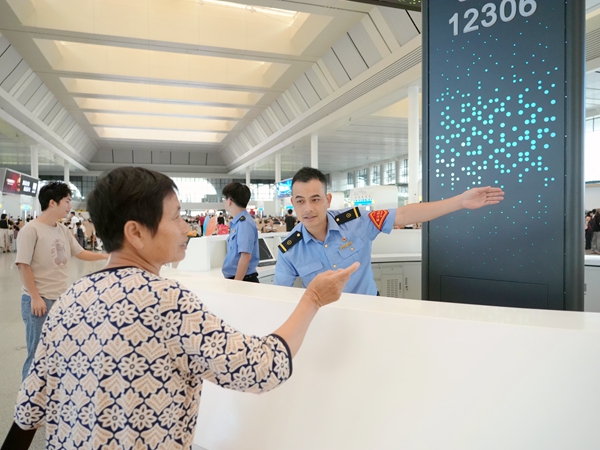 南宁东站客运值班员为旅客引导方向。冯泓珲摄
