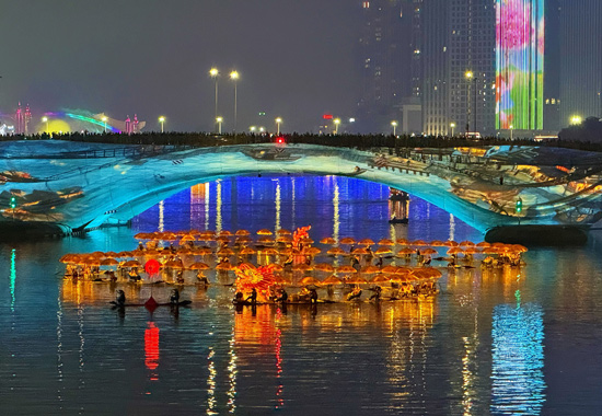 夜幕降臨，流光靈動的龍身、整齊排布的竹筏，與運河古橋等文脈遺跡、現代化濱河夜景交相輝映。