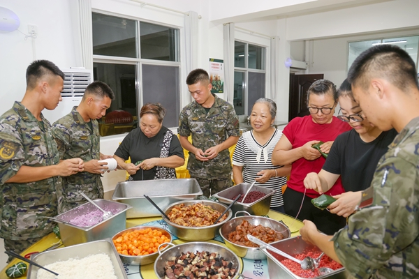武警官兵與駐地群眾共同包粽子。