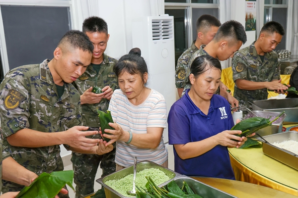 武警官兵與駐地群眾共同包粽子。