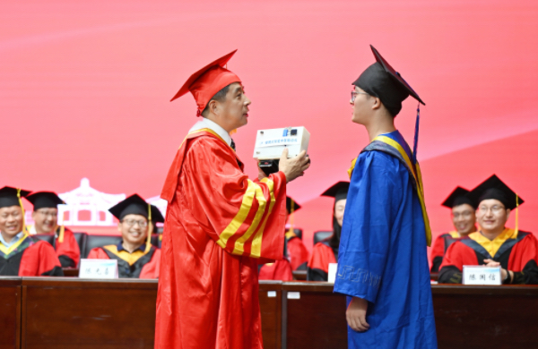桂林電子科技大學生命與環境科學學院碩士畢業生謝立鴻將其自主研發的便攜式智能中醫脈診儀贈送給校長。伍躍麗攝