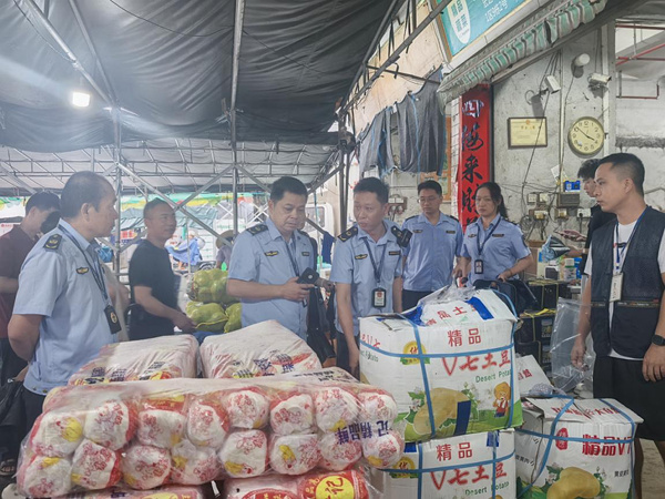 图为执法人员正在检查水果批发门店。