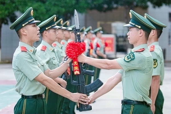 新兵郑重从老兵手中接过钢枪。唐明洋摄