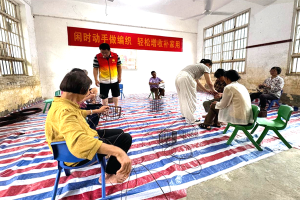 覃宇球在指导村民手工编织。广西幼师供图