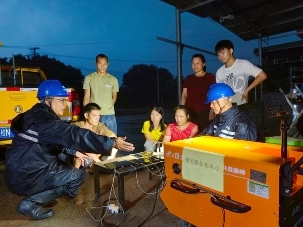 欽州靈山供電局檀圩供電所工作人員將“移動充電寶”運到那隆鎮清水降村委龍門江便民服務點，為群眾手機充電。王麗攝