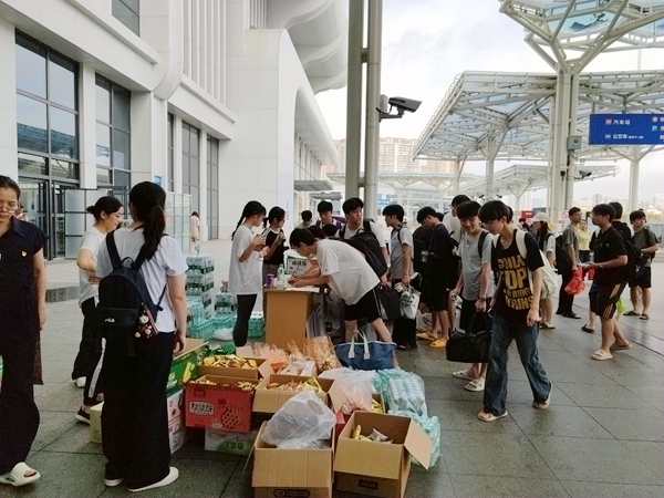 广西物流职业技术学院学生在车站临时点登记乘车方向，领取饮用水、面包等物资。陈海婵摄