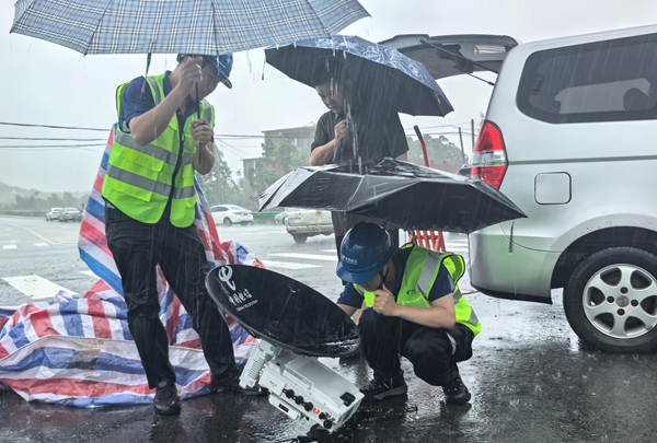 电信保障人员冒着疾风骤雨在信号中断区域调试便携卫星基站无线信号    黄统才 摄