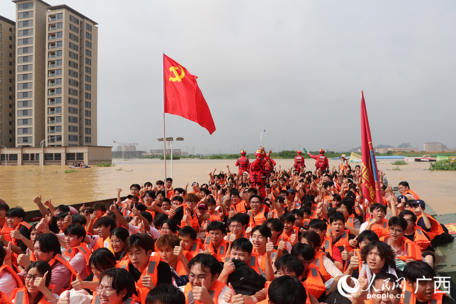 广西物流职业技术学院学生乘坐动力舟桥前往可靠地带，他们竖起大拇指向救援人员致敬。人民网记者 郭振乾摄