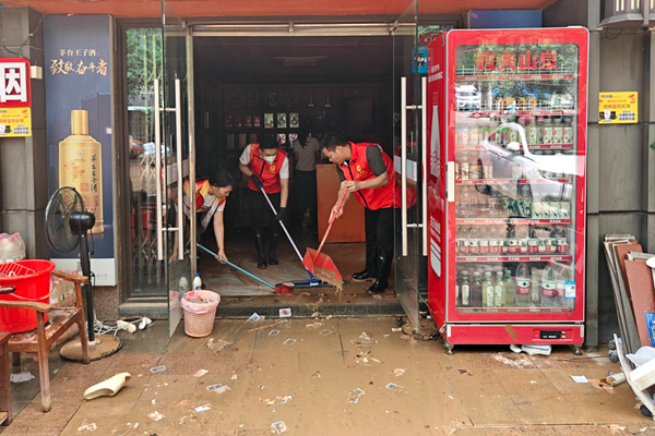志愿者们在帮零售户清扫淤泥、清洁店面。梁君摄