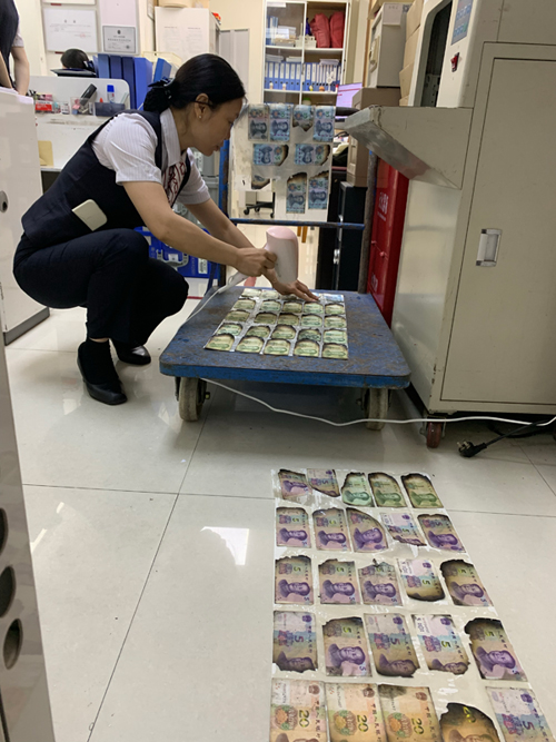 网点工作人员吹干烧焦的纸币。中国银行柳州分行供图