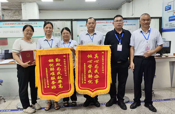 企業向不動產登記中心贈送兩面錦旗，工作人員與企業代表合影。