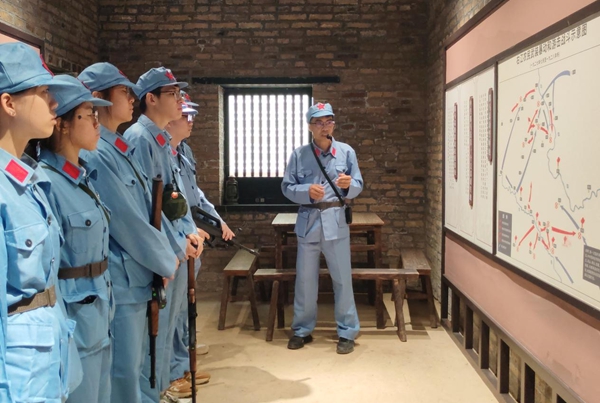 研学团队换上红军服装，认真聆听讲解员讲述革命故事。