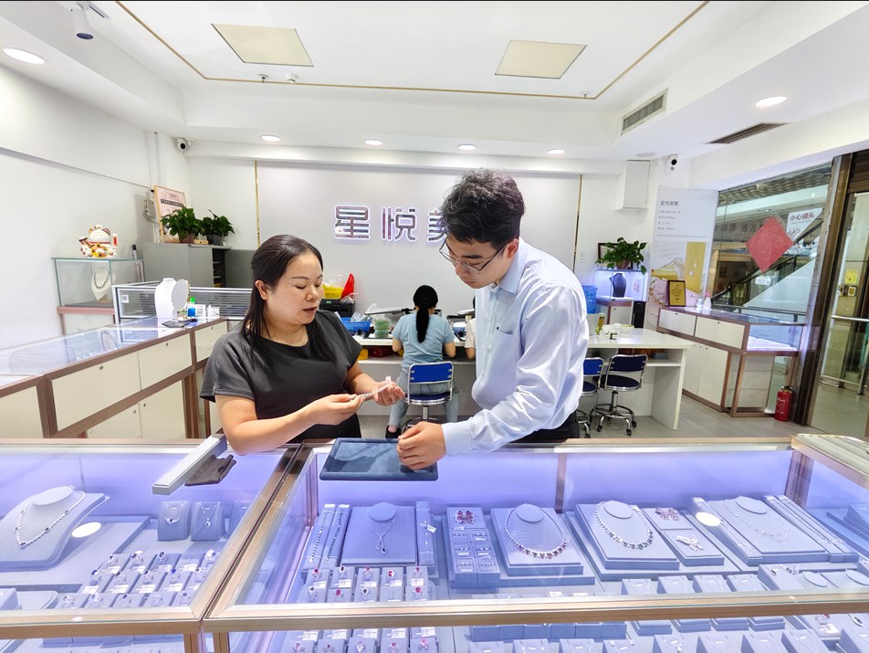 农行客户经理走访人工宝石销售商户。农行梧州分行供图