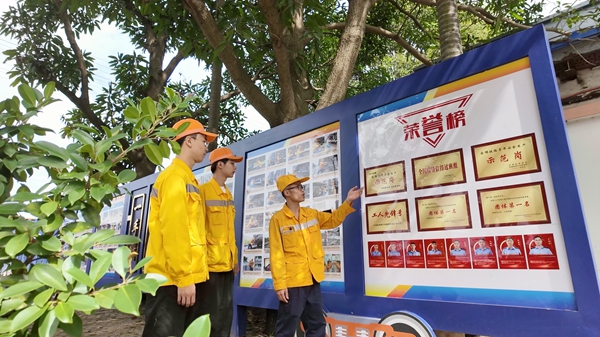 王均权（右）在给职工介绍班组荣誉。覃园介摄