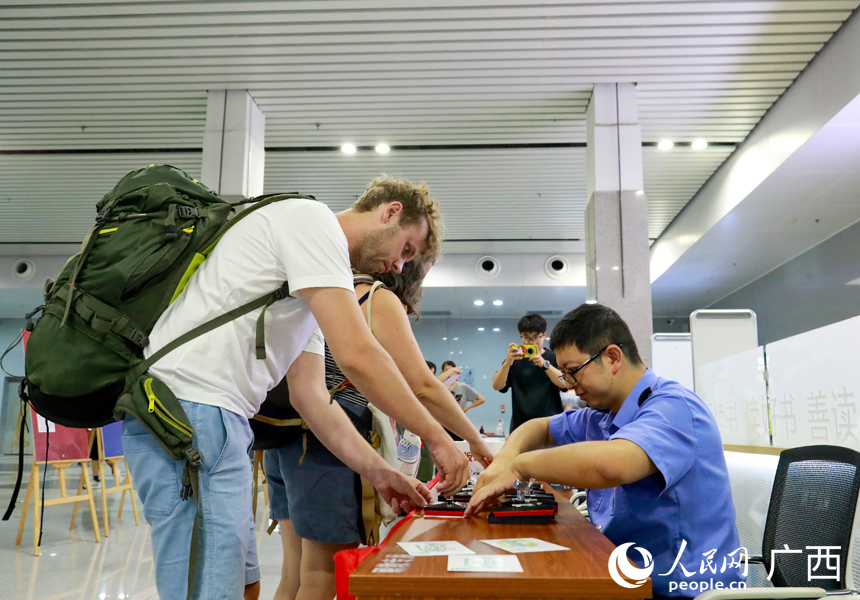 8月11日上午，外籍旅客在桂林站候车室“打卡”高铁文创印章。