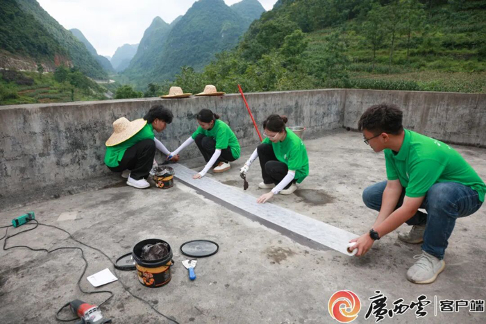 志愿者在都安瑶族自治县村民家中修缮漏水房屋。