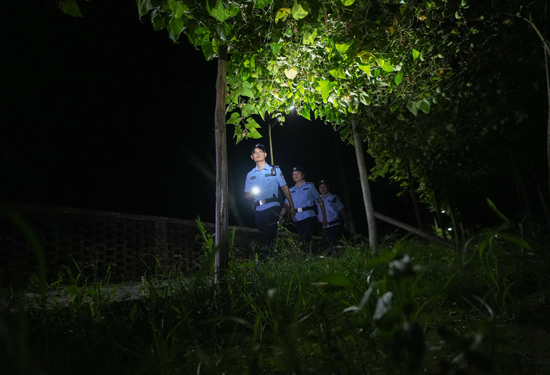 夜间，在龙胜各族自治县乐江镇，民辅警在果园里巡逻。吴倩茜摄