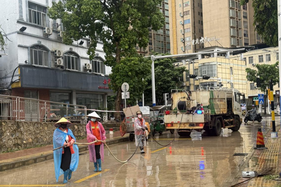 南大路铁路下穿路口，工作人员对路边绿化带、墙根处的垃圾杂物进行清扫清运