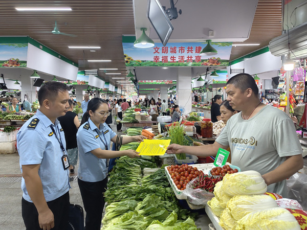 執法人員在農貿市場向商戶宣傳汛期價格相關政策。韋發忠攝
