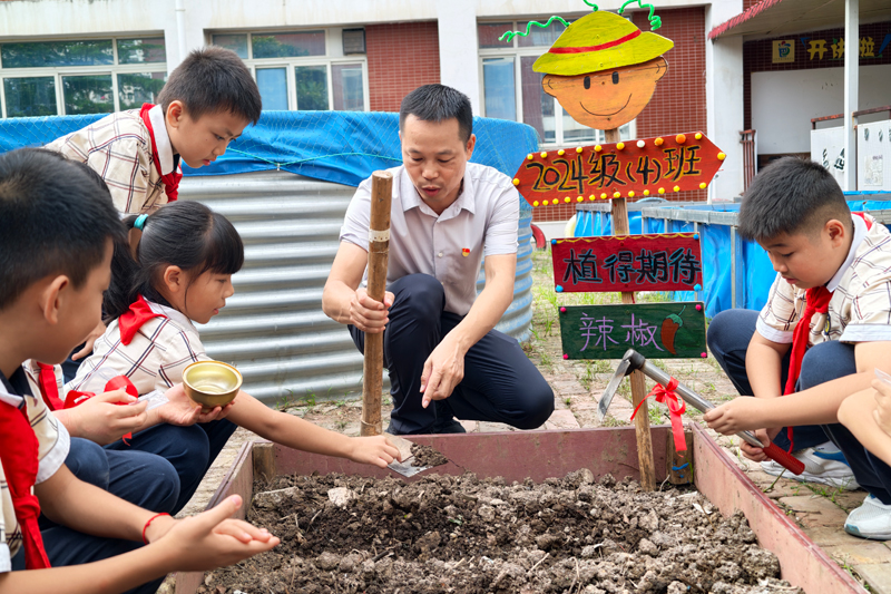校长廖大赞指导学生进行翻土。韦铖摄