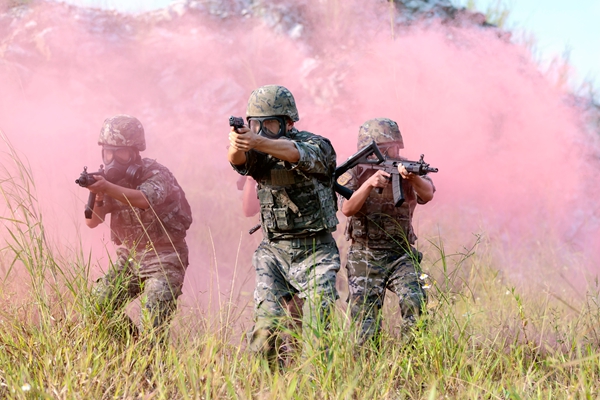 武警官兵穿戴防毒面具通过“封锁线”。