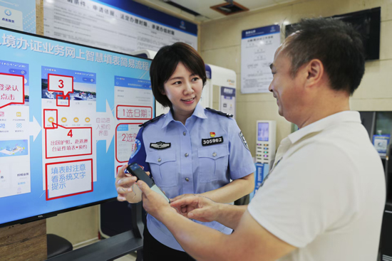 出入境管理支队民警向前来办证的群众介绍网上填表系统。桂林市公安局供图