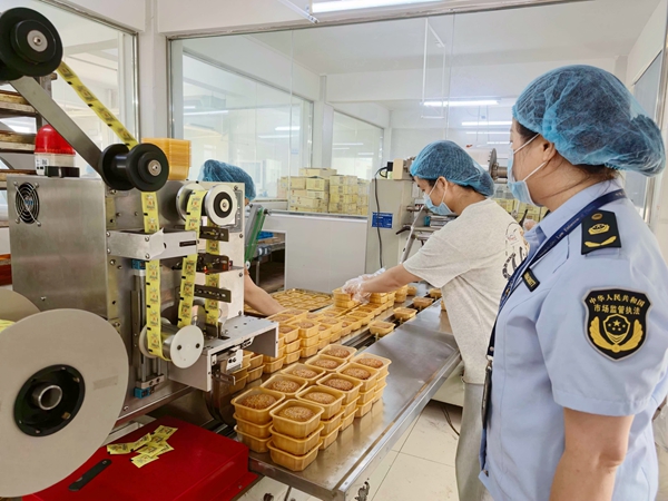 执法人员检查企业月饼生产线。