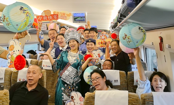 G3618次列車開展中秋游園會活動，列車工作人員與旅客合影。劉媛攝