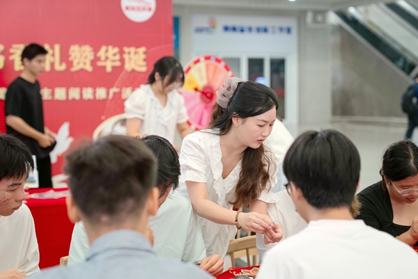 圖書館館員指導旅客參與制作愛國織錦風鈴。趙波攝